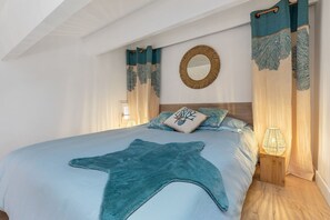 A bedroom with a bed, a round mirror, curtains, and a bedside lamp.