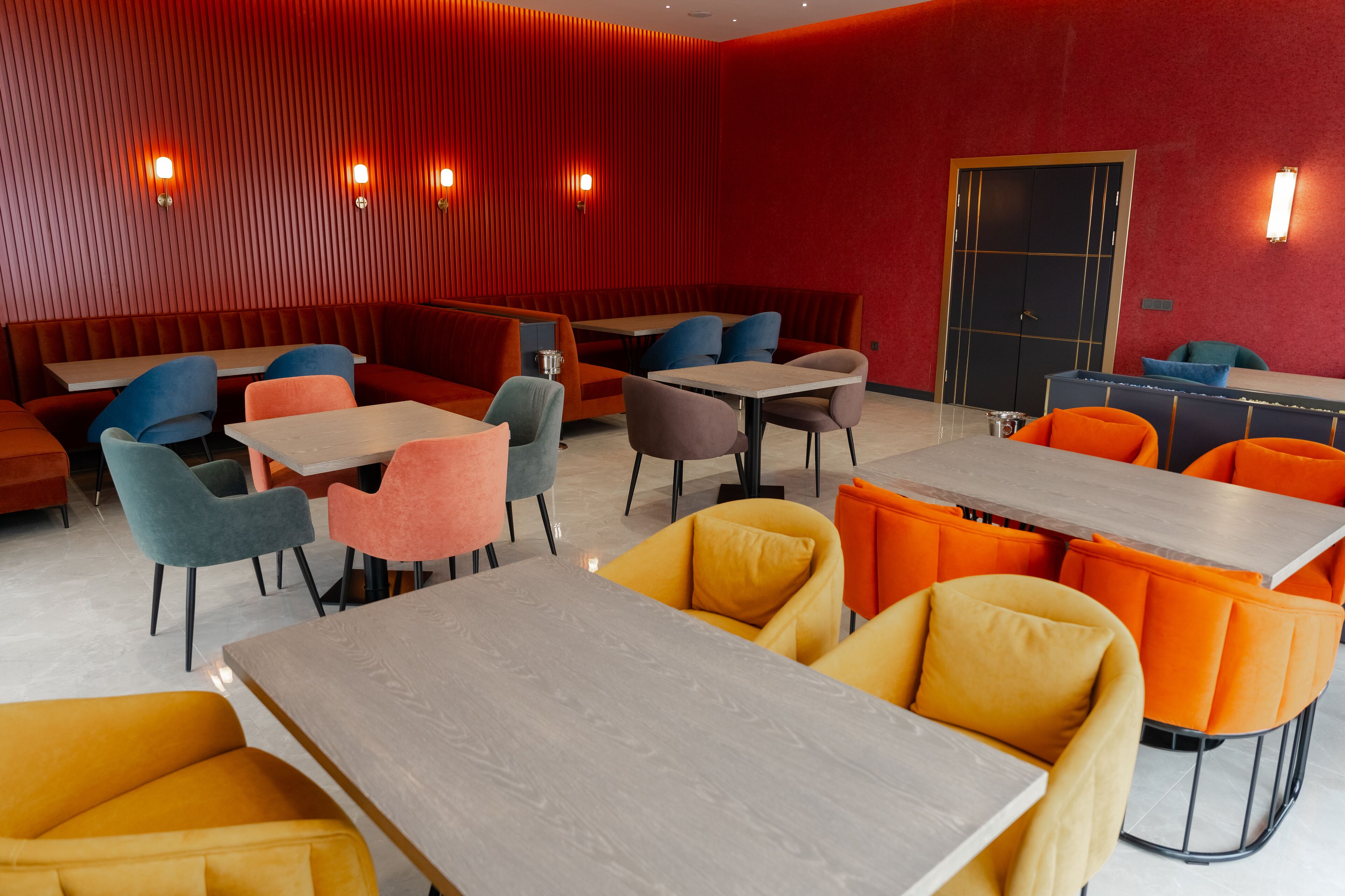 Un interior de restaurante moderno con cabinas y mesas, paredes rojas e iluminación cálida.