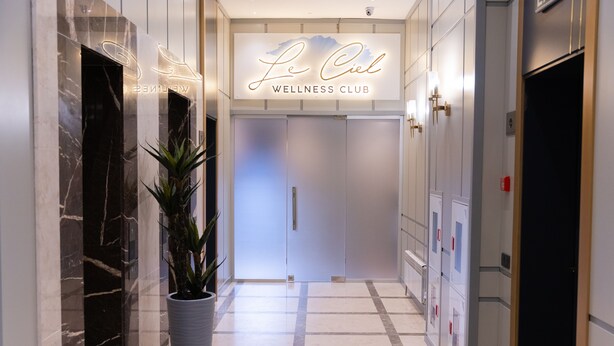 A hallway with a marble floor, a potted plant, and a sign for Le Ciel Wellness Club. - Park Dedeman Almaty (Almaty)