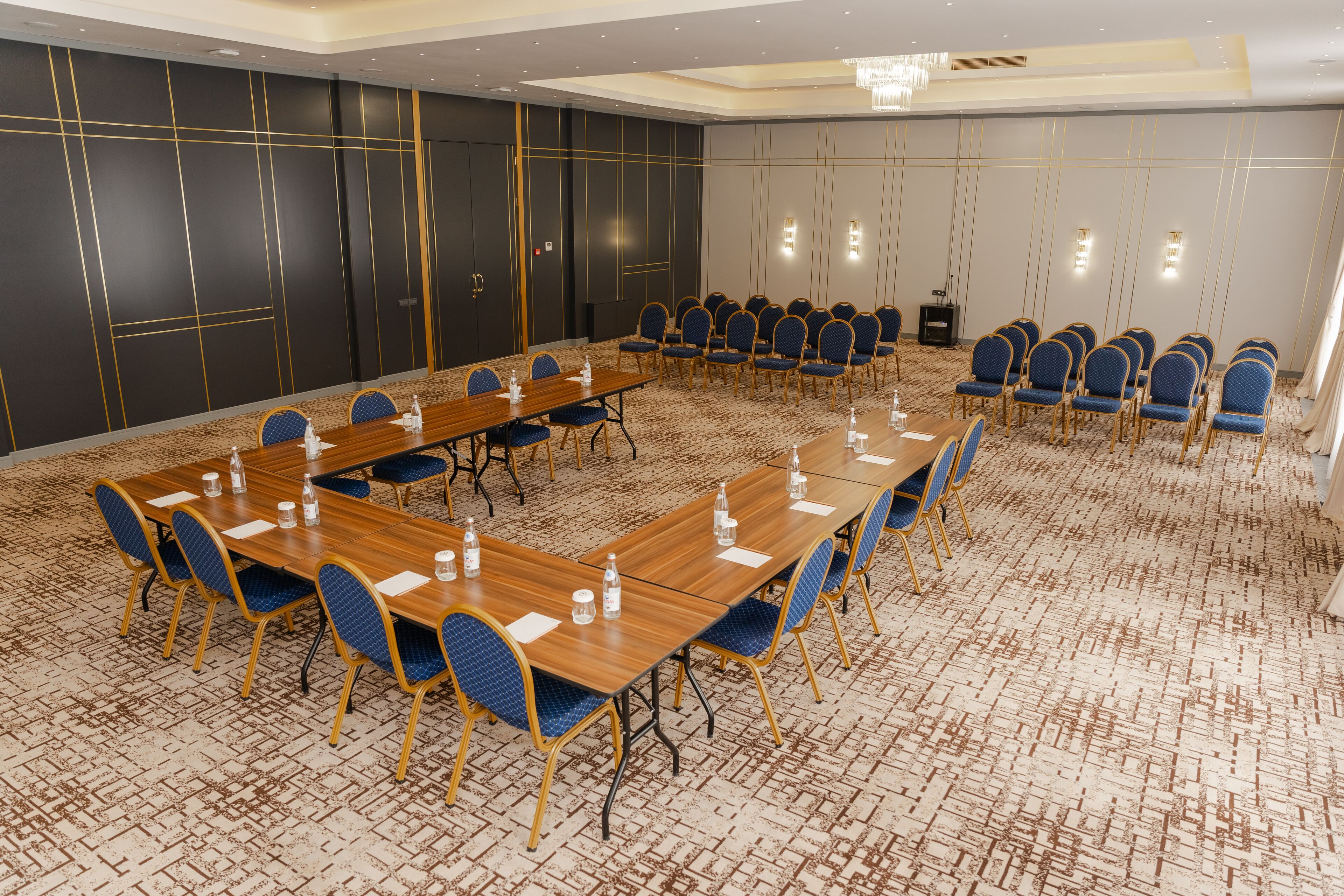 A conference room with a long table and chairs, carpeted floor, and a dark wall with gold lines.