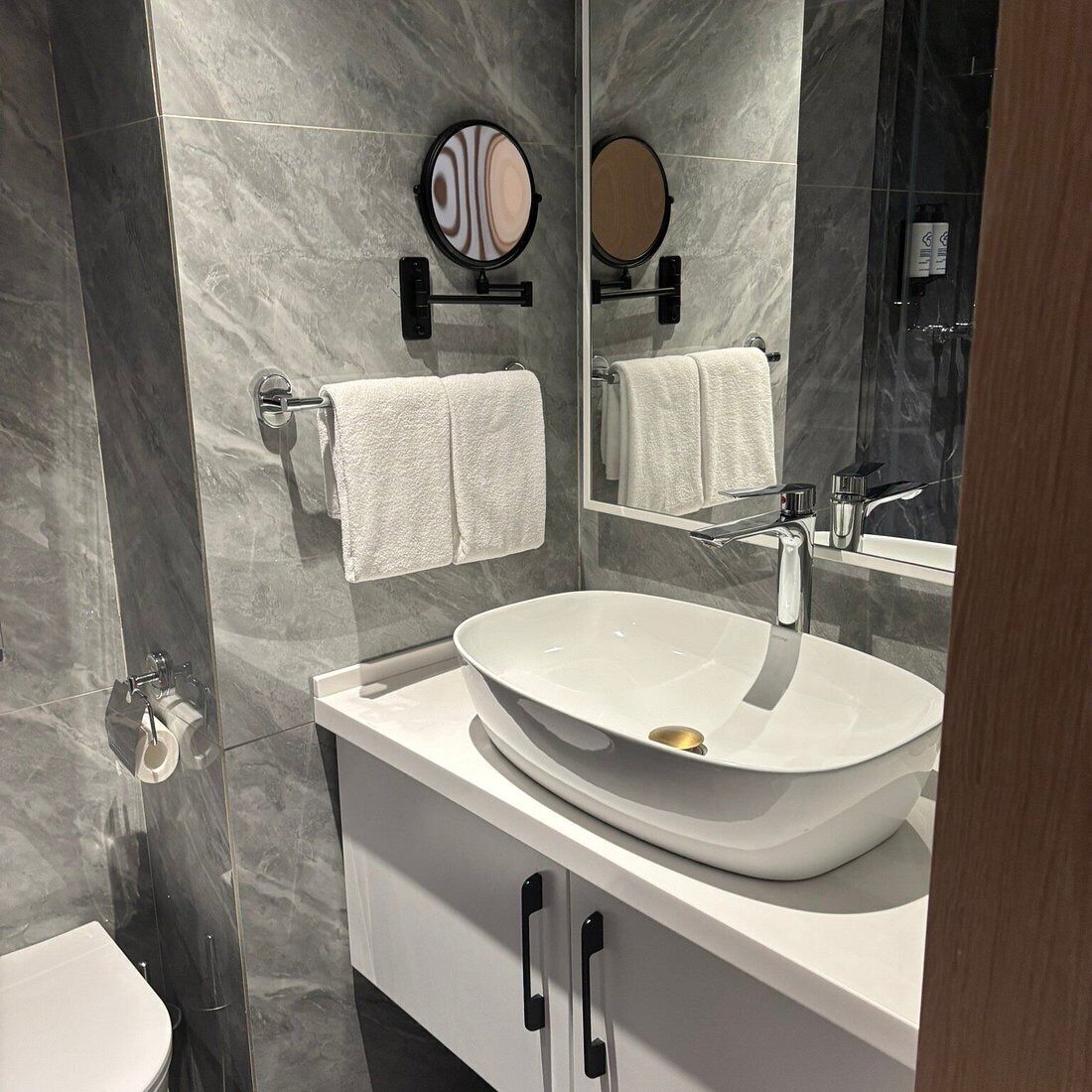 A modern bathroom with a large mirror, a vessel sink, and a toilet.