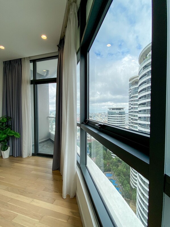 Enjoy city views from the large window in this stylish room, featuring a balcony and potted plant.