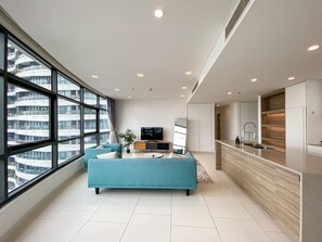 Relax in this stylish living area with a large window offering a view of the city, a comfortable sofa, flat-screen TV, and kitchenette.