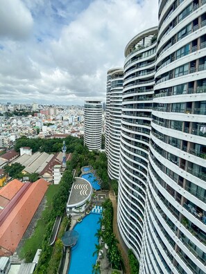 Residents enjoy balconies and a resort-style pool surrounded by lush greenery.