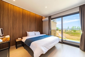 Ein modernes Hotelzimmer mit einem großen Bett, einem Schreibtisch mit Computer und Blick ins Freie.
