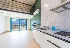 Eine moderne Küche mit einem großen Fenster, einem Einbauherd und Blick ins Freie.