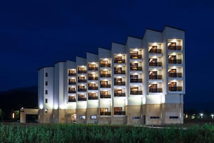 A multi-story hotel with balconies and illuminated windows at night.