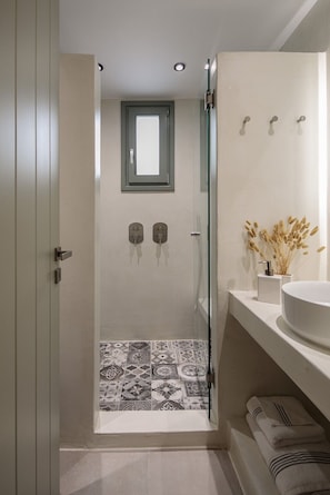 Un bagno con doccia, lavandino, specchio e finestra.