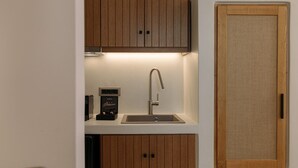 Une cuisine compacte avec des meubles en bois, un évier en acier inoxydable et une machine à café.
