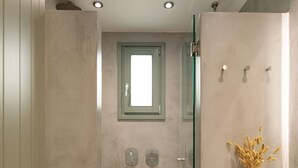 Une salle de bain moderne avec une douche à parois de verre, un grand lavabo et une fenêtre située au-dessus de la douche.