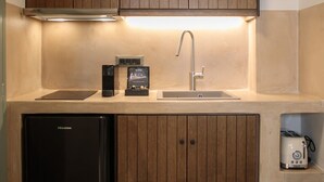 Une cuisine compacte avec des meubles en bois, un évier encastré, un réfrigérateur noir et une machine à café.