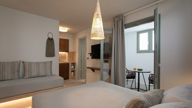 Une chambre d’hôtel comprenant un lit, un canapé, une table à manger avec des chaises, une télévision et un coin cuisine.