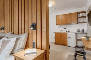 Une cuisine moderne avec des meubles en bois, un réfrigérateur blanc et un petit coin repas comprenant une table et des chaises.
