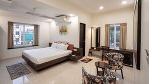 A hotel room with a large bed, a desk with a chair, a small table, and a mirror. - Springdale Suites - Nagpur (Nagpur)