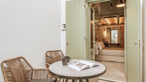A room with a round table, two wicker chairs, a book, and a mug.