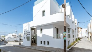 A modern white building with Makava Suites signage, a balcony, and a clear sky.
