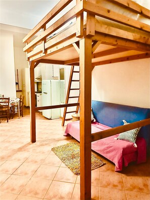 A room with a bunk bed, a dining area, and a kitchen.