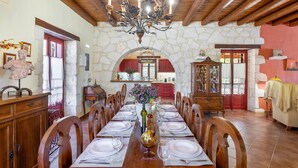A dining room with a stone wall, wooden ceiling, and a chandelier.