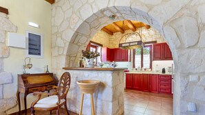 A kitchen with stone walls, wooden furniture, and red cabinets.
