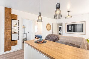Eine moderne Küche mit Holzakzenten, Pendelleuchten und einem Essbereich mit einer Couch und einem großen, gerahmten Kunstwerk.