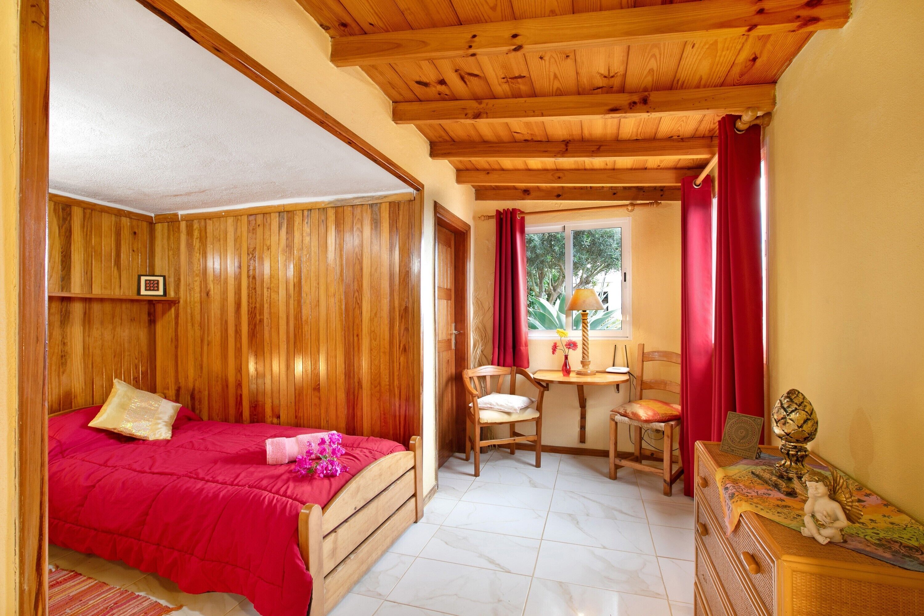 A bedroom with a wooden bed, a small desk, and a chair.