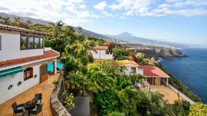 Une propriété située sur la côte, dotée d’une terrasse, d’une piscine et offrant une vue sur l’océan et une montagne.
