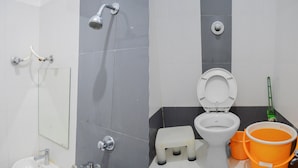 A modern bathroom with a shower, toilet, sink, and two orange buckets. - Hotel Royal Palace (Ujjain)