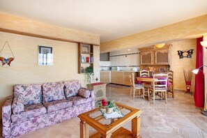 Uma sala de estar com sofá, mesa de centro e um espaço de jantar com cadeiras e mesa.