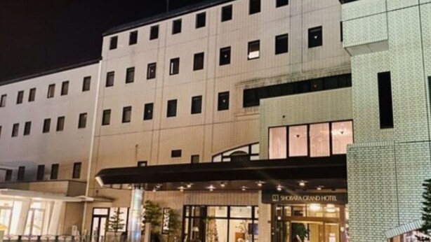 A hotel with a large entrance, a handicap parking space, and a sign for the Shobara Grand Hotel.