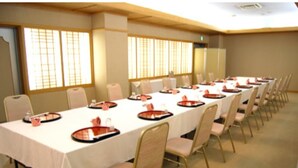 A conference room with a long table, chairs, and a window with blinds.