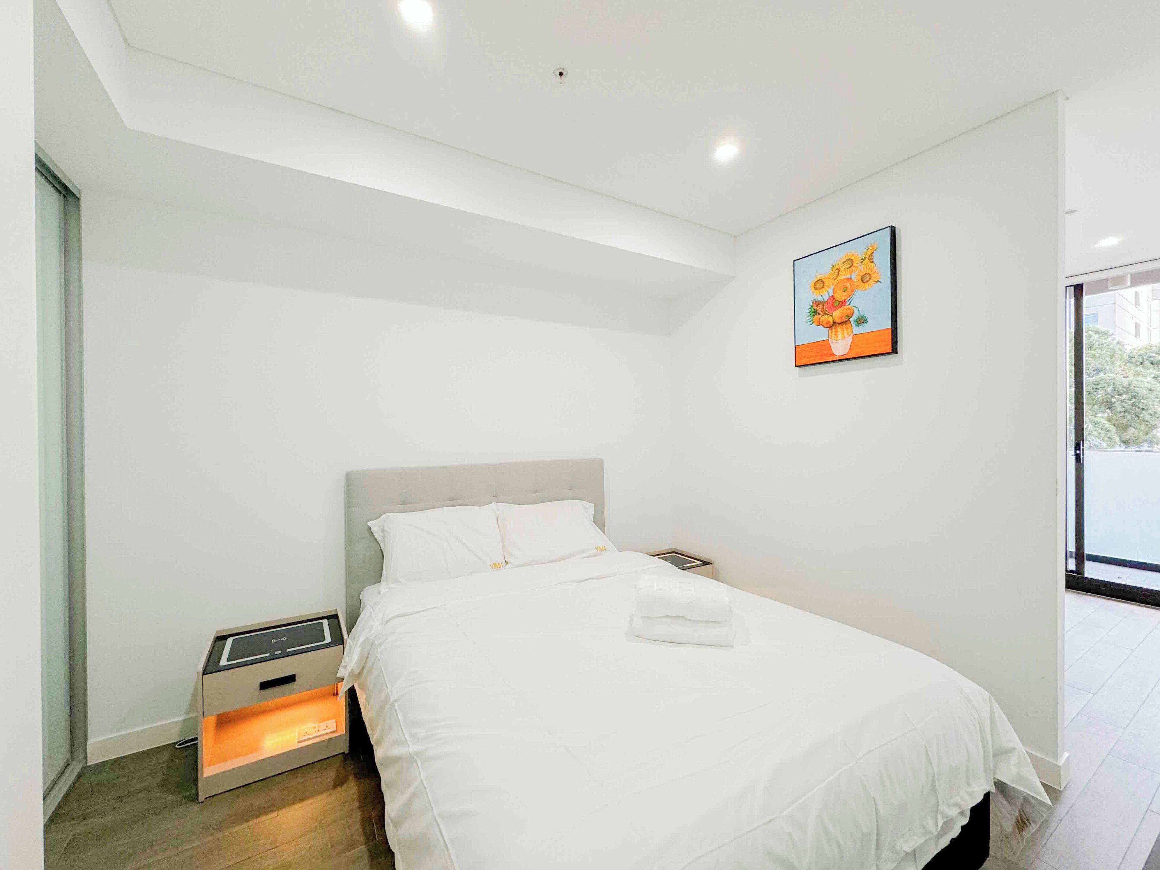 A modern bedroom with a bed, bedside table, and a small heater.