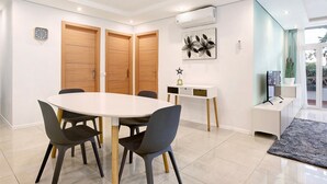 Un comedor moderno con una mesa redonda, sillas y un armario blanco.