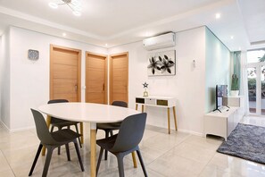 A modern dining area with a round table, chairs, and a white cabinet.