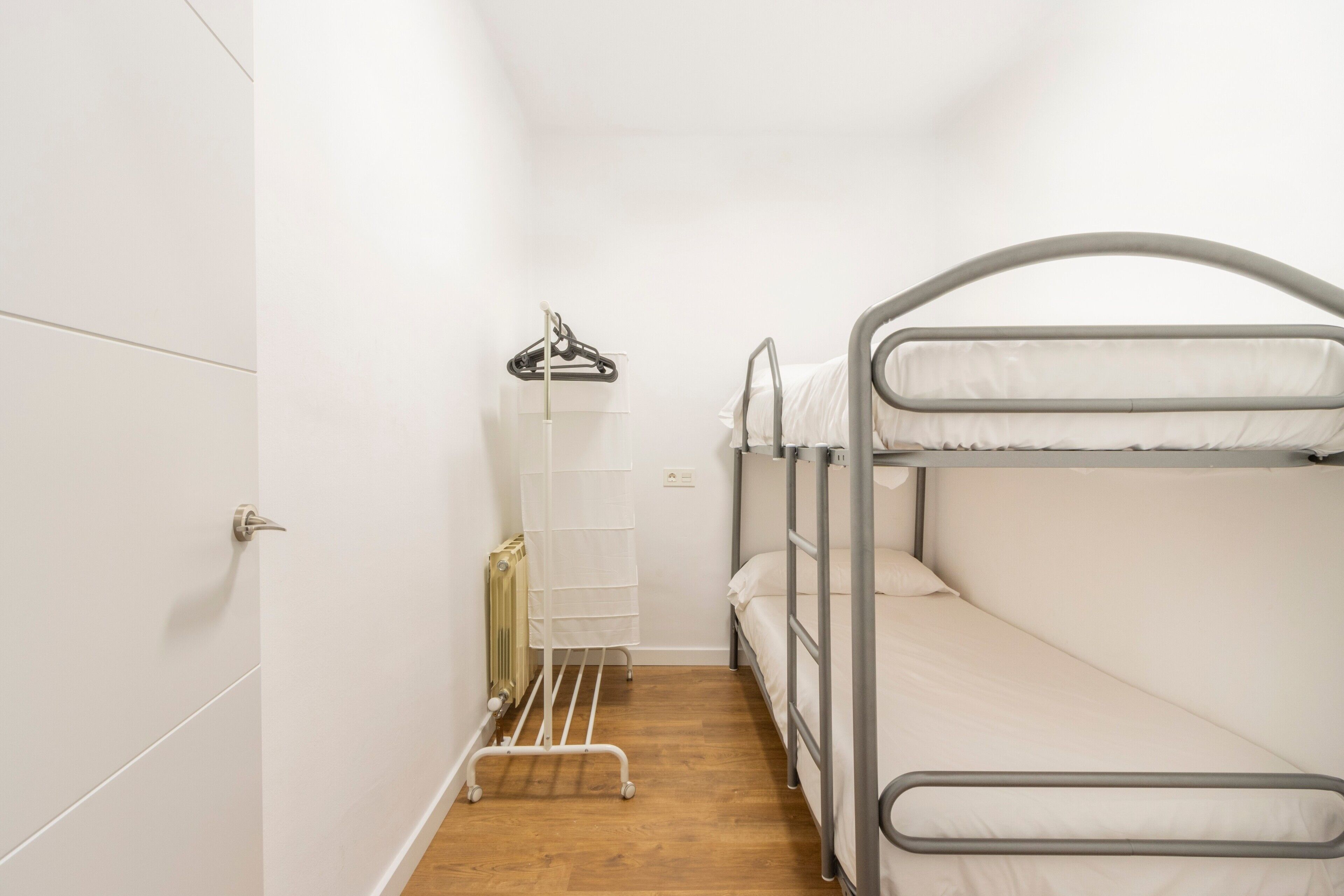 Habitación con literas, un radiador, un tendedero y una puerta.