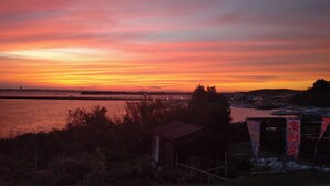 Zonsondergang boven een waterpartij met een klein gebouw op de voorgrond.
