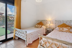 A bedroom with two beds, a window, and a view of the outside.