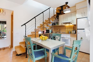 A compact kitchen with a dining area, a staircase, and a view of the outdoors.