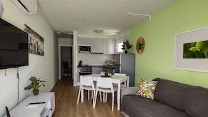 A modern living room with a grey sofa, a small white table, and a TV mounted on the wall.
