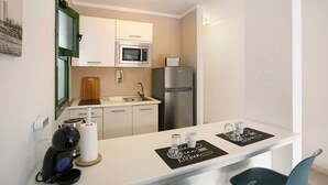 A compact kitchen with a microwave, refrigerator, and a small dining area with a table and chairs. - Vacation Apartment 'Dreams' with Sea View, Shared Pool and Wi-Fi (Puerto Rico)