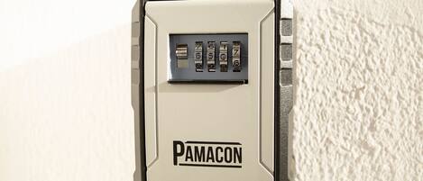 A wall-mounted security device with a keypad and the brand name 'PAMACON' visible.