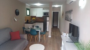 A compact living space with a kitchenette, a dining area, a sofa, and a TV. - Vacation Apartment 'Dreams' with Sea View, Shared Pool and Wi-Fi (Puerto Rico)