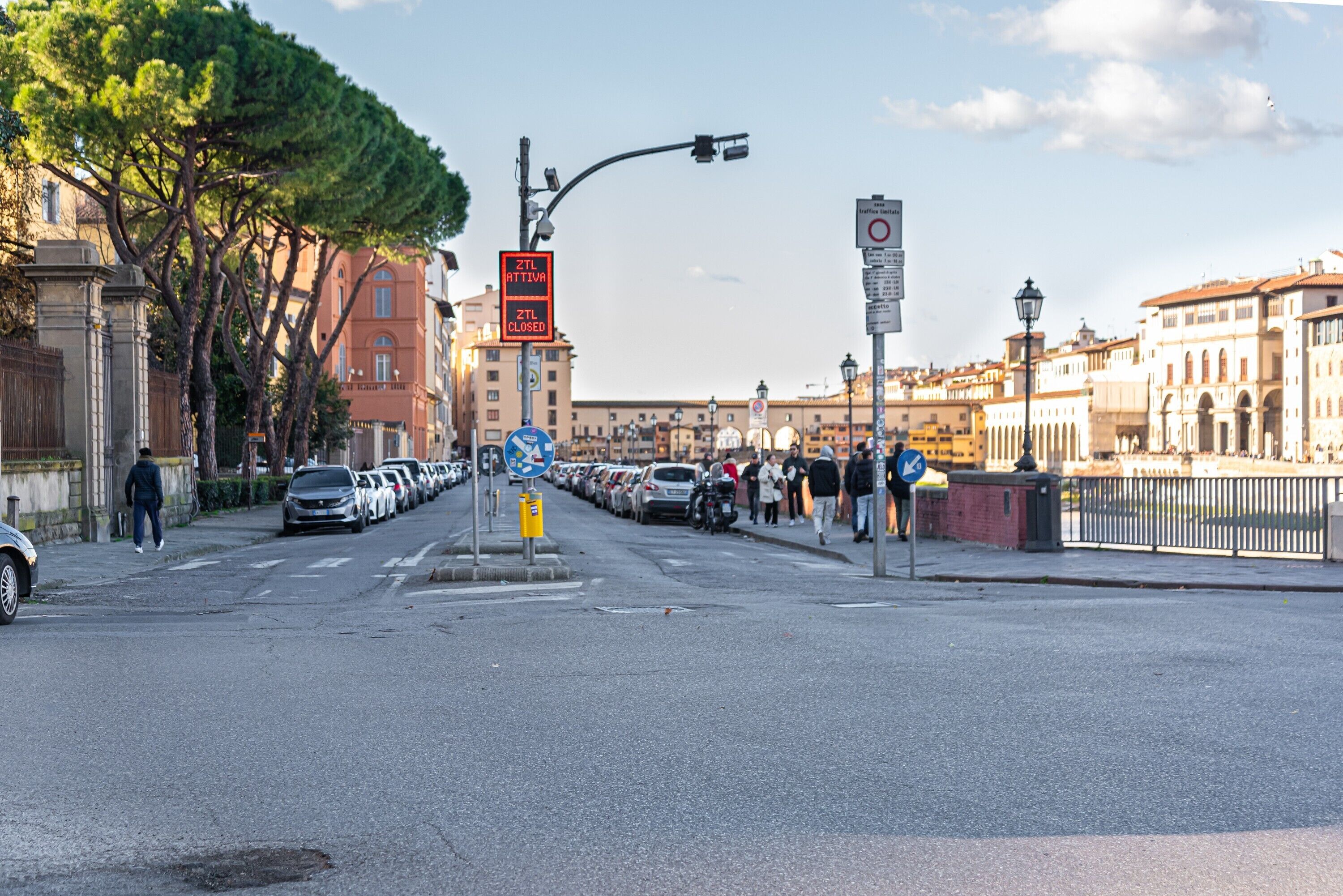 A street with parked cars, a pedestrian crossing, and a closed traffic sign.