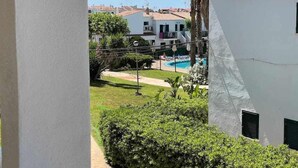 Vista de una zona residencial con piscina, edificios blancos y abundante vegetación.