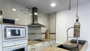 A modern kitchen with a built-in microwave, oven, and stainless steel range hood. - Macarelleta- Apartamento con Piscina (Cala Blanes)