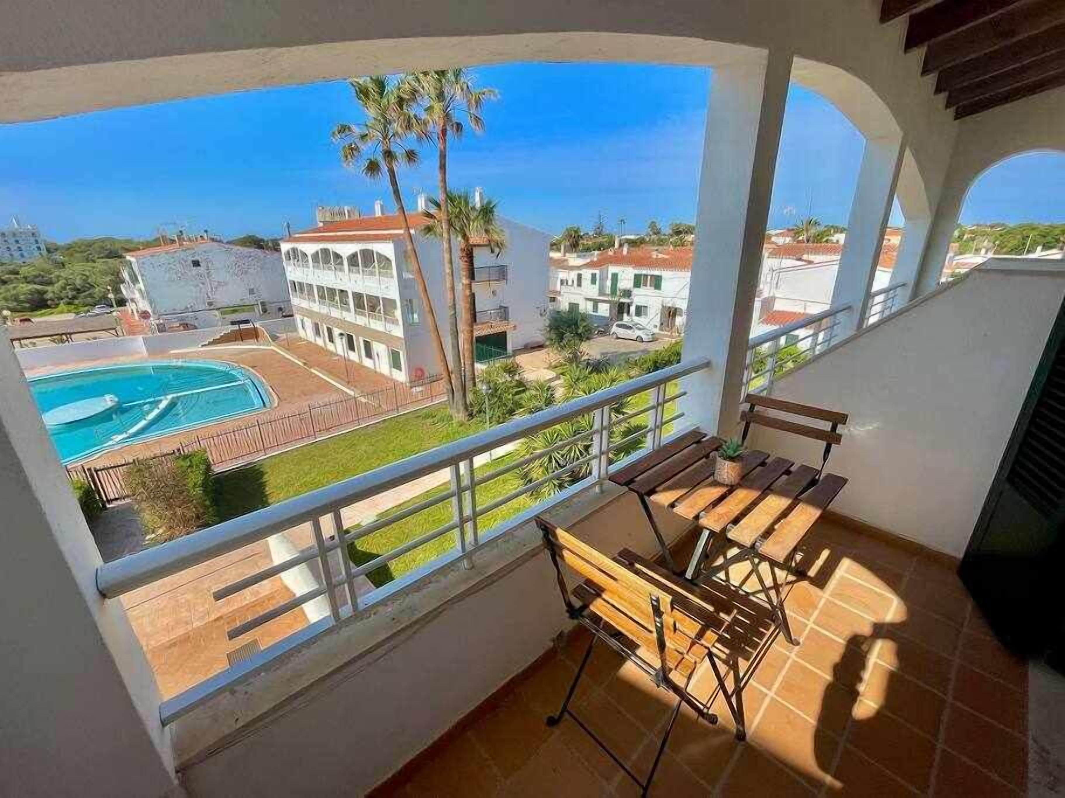 A balcony with a view of a swimming pool and surrounding buildings.