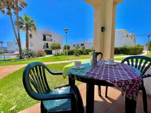Une terrasse extérieure avec une table dressée pour deux personnes, des chaises et une cafetière.
