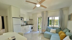 Un espacio habitable compacto con kitchenette, comedor y sofá con cojines.