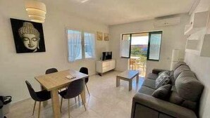 Una sala de estar moderna con comedor, un sofá, un televisor y obras de arte en las paredes.