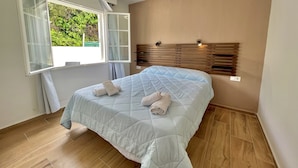 A bedroom with a bed, a window with curtains, a ceiling fan, and a wooden headboard. - Gregal - Castell Sol - Arenal de Castell (S'Arenal D'En Castell (Menorca) (Urbanitzacio))