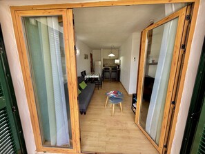 Una habitación con puerta corredera de madera, un sofá, una mesa de comedor con sillas y una mesita con revistas.